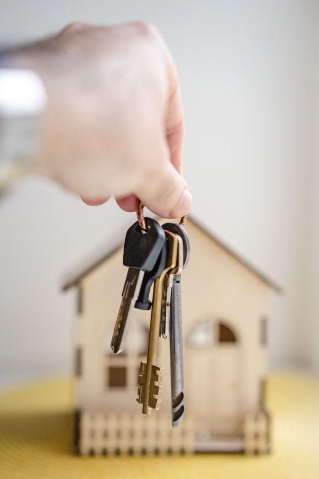 person holding keys in front of house model